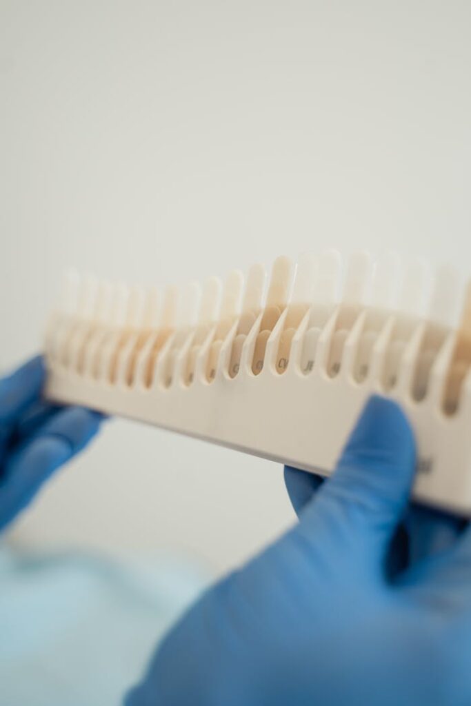 pexels photo 5355904 Blue gloved hands holding a dental shade guide in a dental clinic setting.